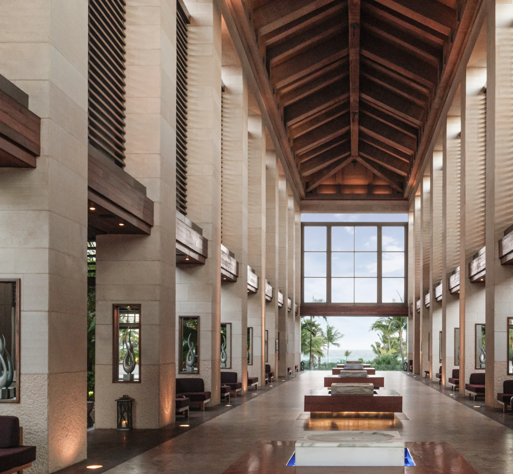 The Cove lobby, its timber ceiling and stone columns opening onto palms and the ocean