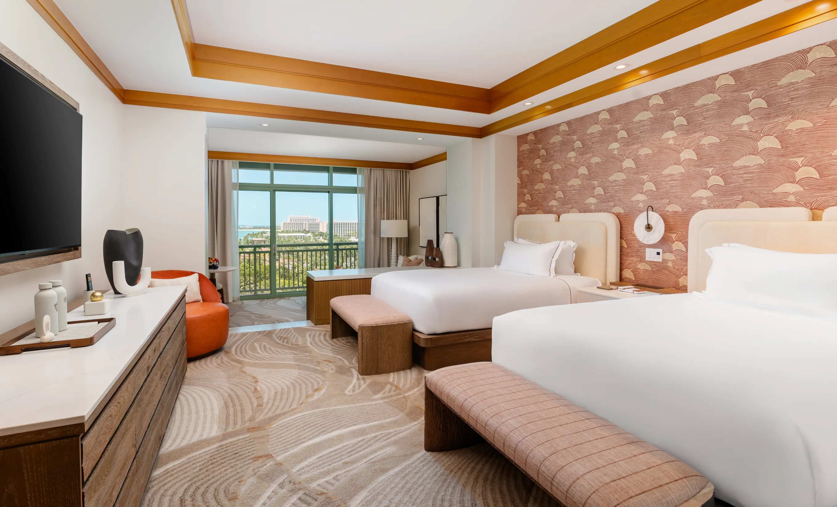 A Cove suite with two queen beds, a coral-patterned feature wall and a terrace beyond